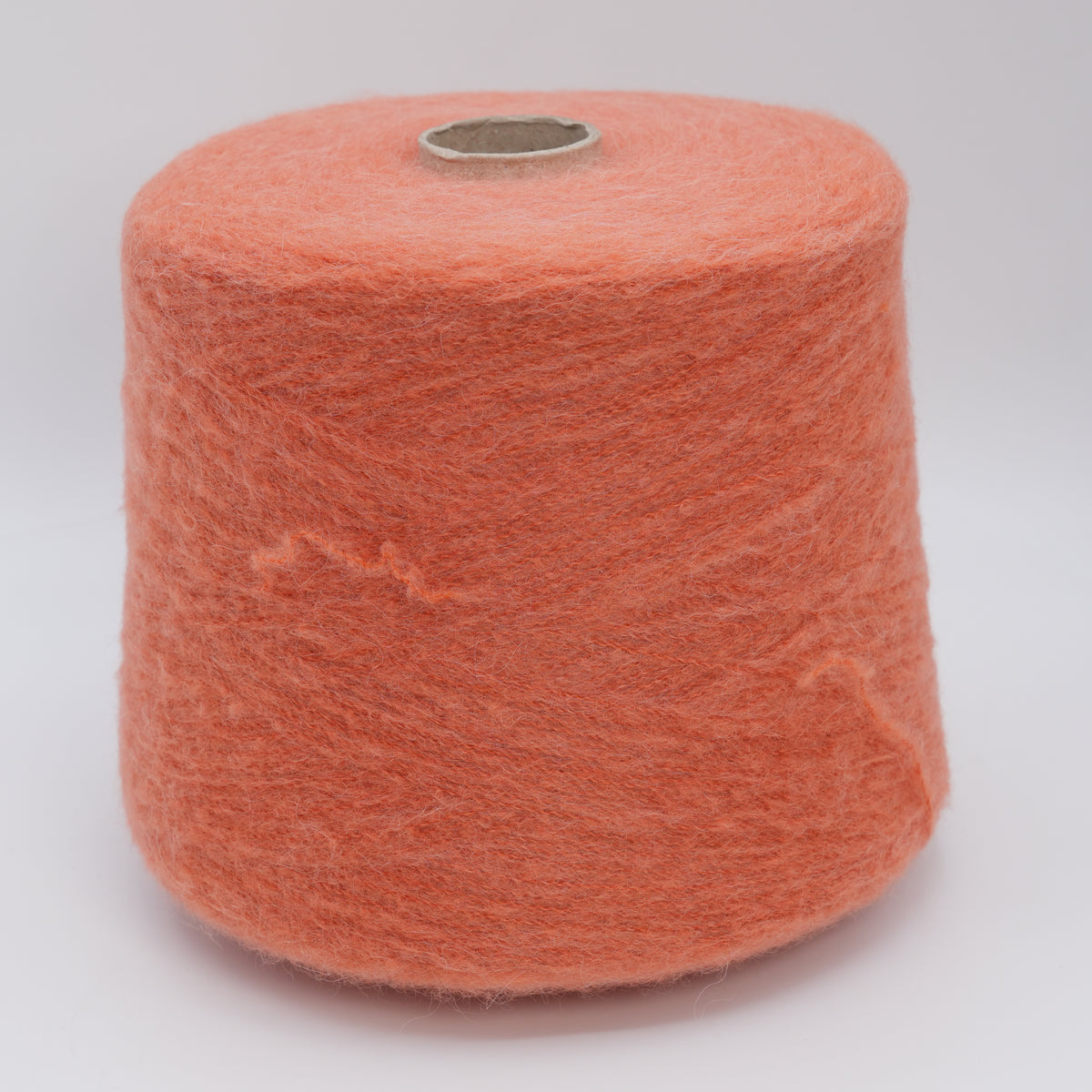 Cone of Nuage 8100 fluffy alpaca blend yarn in Peach Juice.