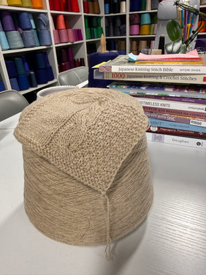 Cone and knitted swatch of Liberty 2PLY 2/14 alpaca and merino blend yarn in Warm Sand.