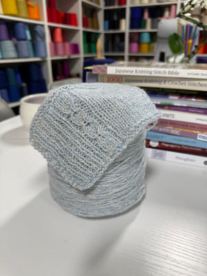 Cone and knitted swatch of Monviso 2/8000 tweed wool blend yarn in gray.