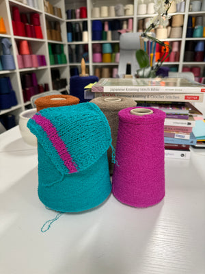 Cones and knitted swatches of Boucle Fine 1/13000 wool and polyamide blend yarn in Turquoise Drift and Magenta Pulse.