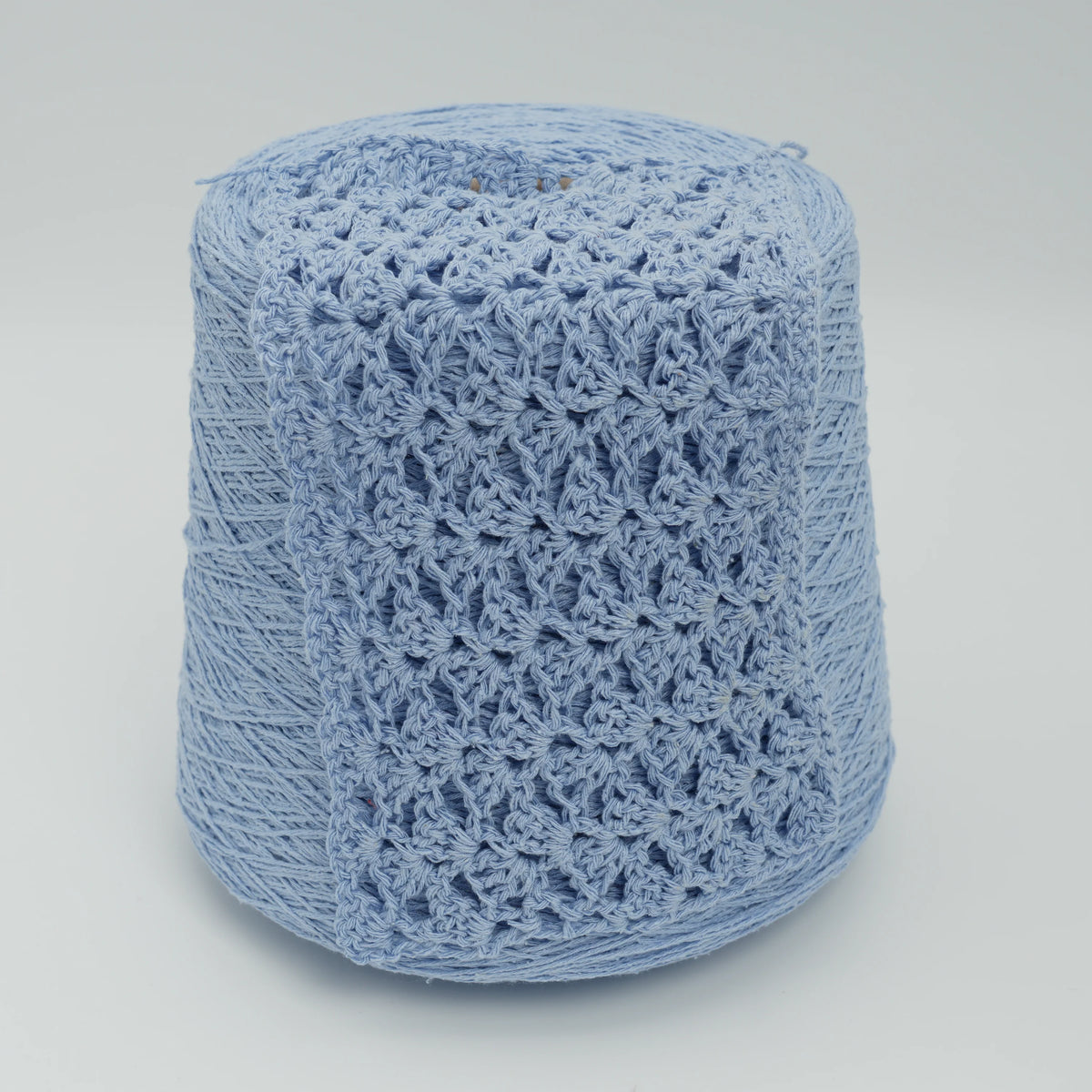 Cone and knitted swatch of Bourette Silk 4000 100% silk yarn in pale blue.
