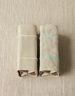 Cocoknits Accessory Roll in Gray partially rolled with adjustable elastic closure and storage pouches visible