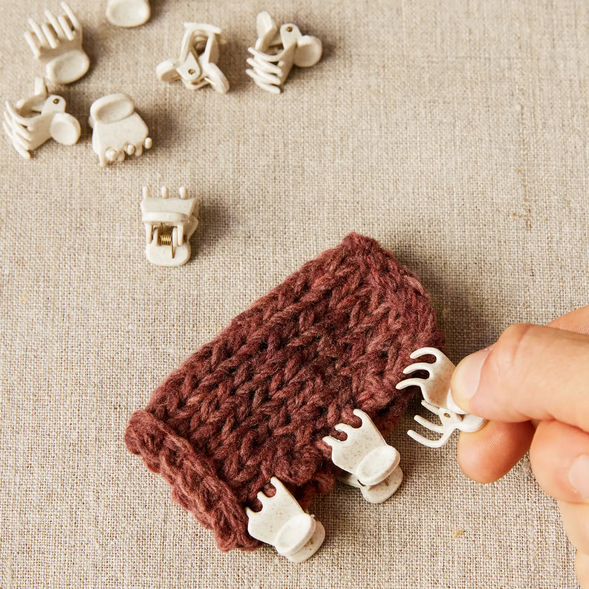 Cocoknits Claw Clips attached along the edge of knitted fabric to hold layers securely while seaming