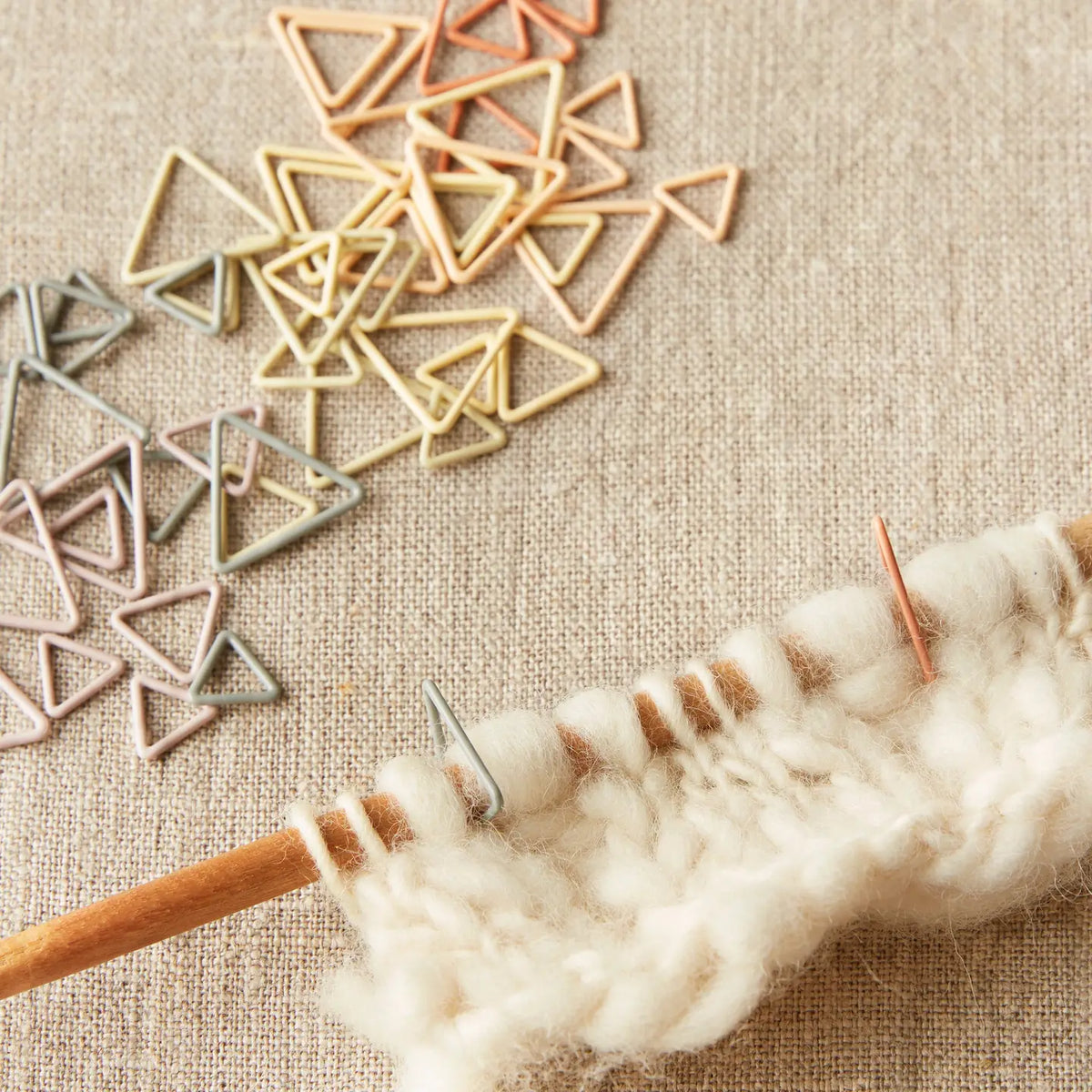 Cocoknits Earth Tone Triangle Stitch Markers shown in use on a knitting project with needles and yarn