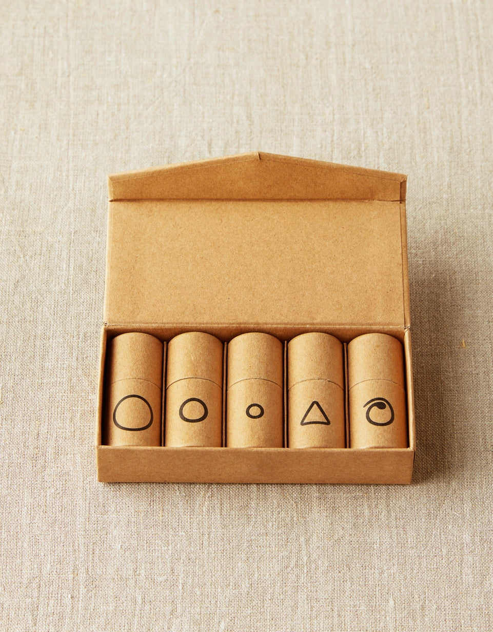 Cocoknits Flight of Stitch Markers with five labeled tubes in an open kraft storage box