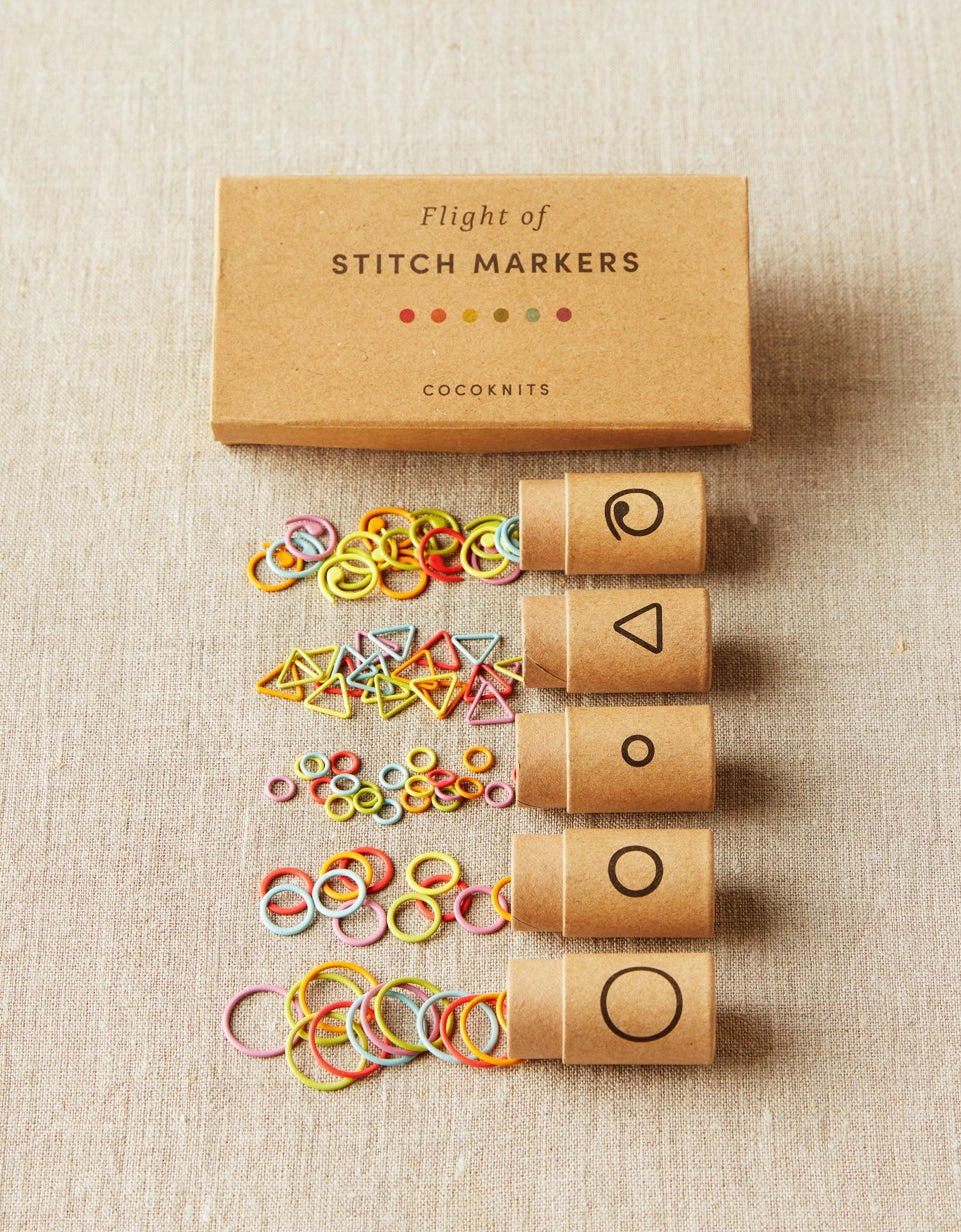 Cocoknits Flight of Stitch Markers rainbow collection displayed with five reusable storage tubes