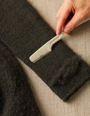 Cocoknits Fuzz Off Comb original being used to remove pills and fuzz from fabric