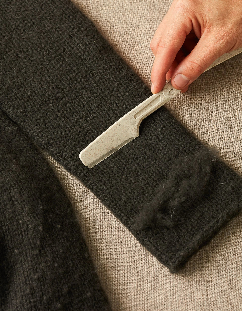 Cocoknits Fuzz Off Comb original being used to remove pills and fuzz from fabric