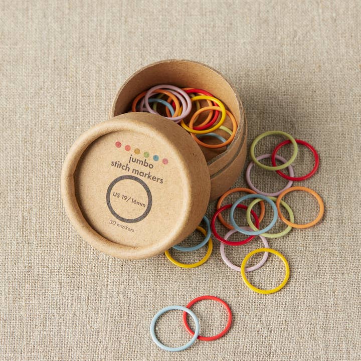 Cocoknits Jumbo Stitch Markers in six colors displayed with their open wooden storage container