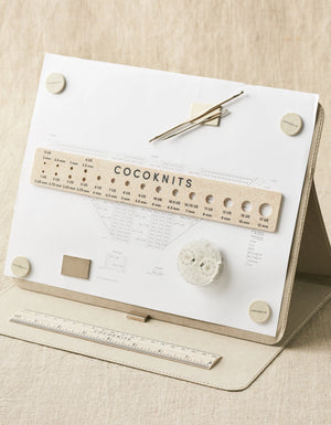Cocoknits Maker's Board in Gray holding a knitting pattern, ruler, and magnetic tools