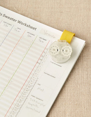Cocoknits Maker's Clip in Yellow holding knitting pattern pages