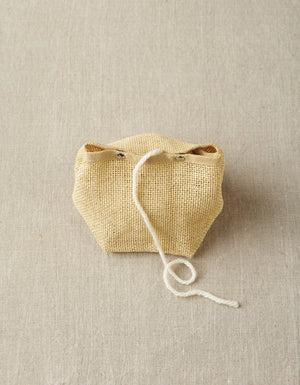 Cocoknits Natural Mesh Bag holding yarn with the working strand feeding through the opening