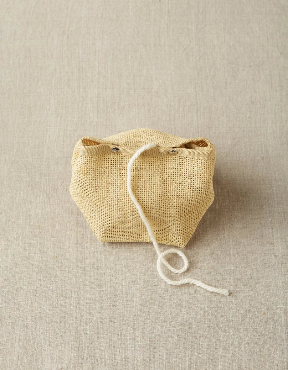 Cocoknits Natural Mesh Bag holding yarn with the working strand feeding through the opening