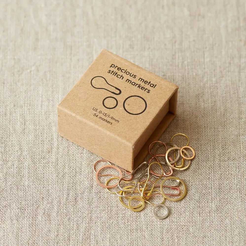 Cocoknits Precious Metal Stitch Markers with kraft box and metallic markers displayed beside it