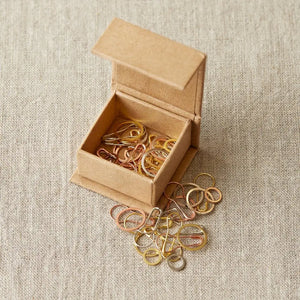 Cocoknits Precious Metal Stitch Markers displayed in an open kraft magnetic box