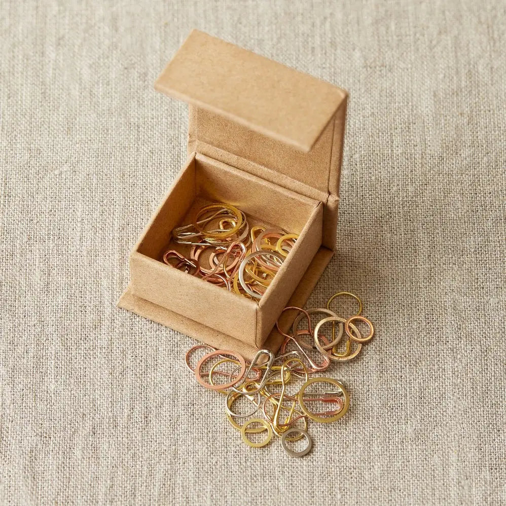 Cocoknits Precious Metal Stitch Markers displayed in an open kraft magnetic box