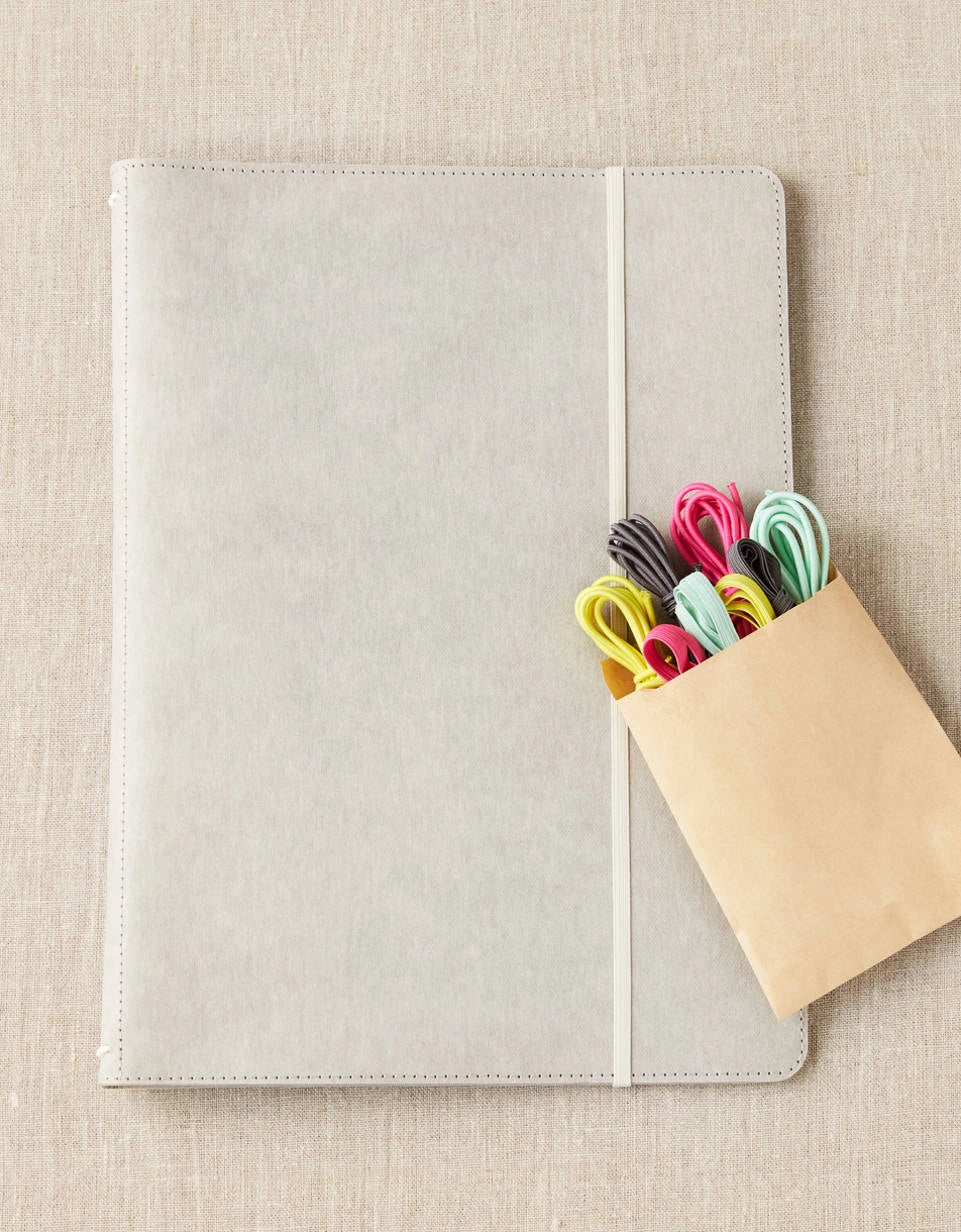 Cocoknits Project Portfolio with colorful knitting accessories in a paper pouch