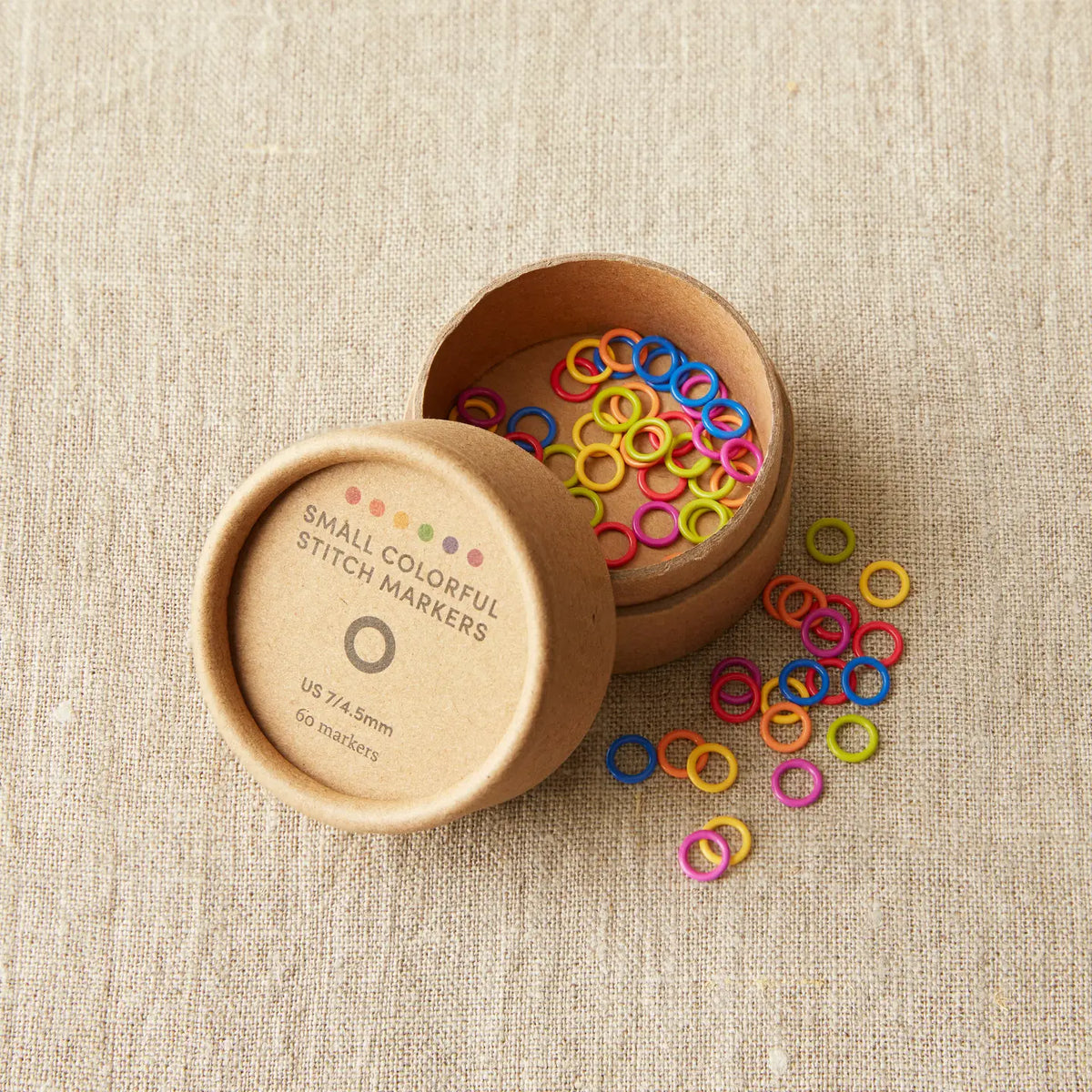 Colorful Cocoknits Small Round Stitch Markers spilling from their kraft paper storage container
