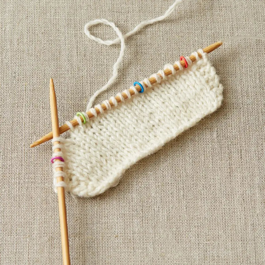 Cocoknits Small Round Stitch Markers shown on knitting needles with a light-colored work in progress