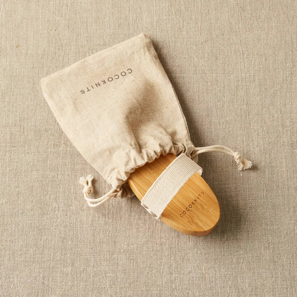 Cocoknits Sweater Care Brush. Wooden brush partly removed from its drawstring storage bag.