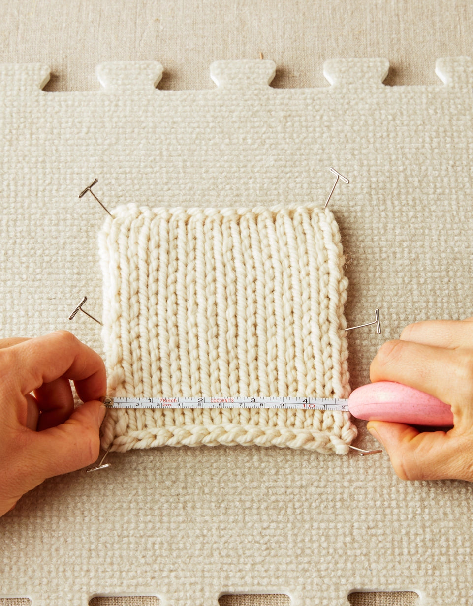 Cocoknits T-Pins. Hands stretching a knitted swatch secured with T-pins.