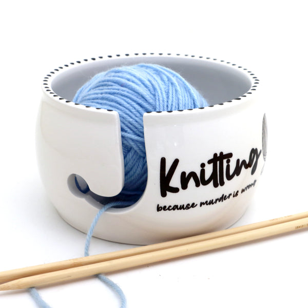 Knitting Because Murder Is Wrong Yarn Bowl. White yarn bowl holding blue yarn beside knitting needles.