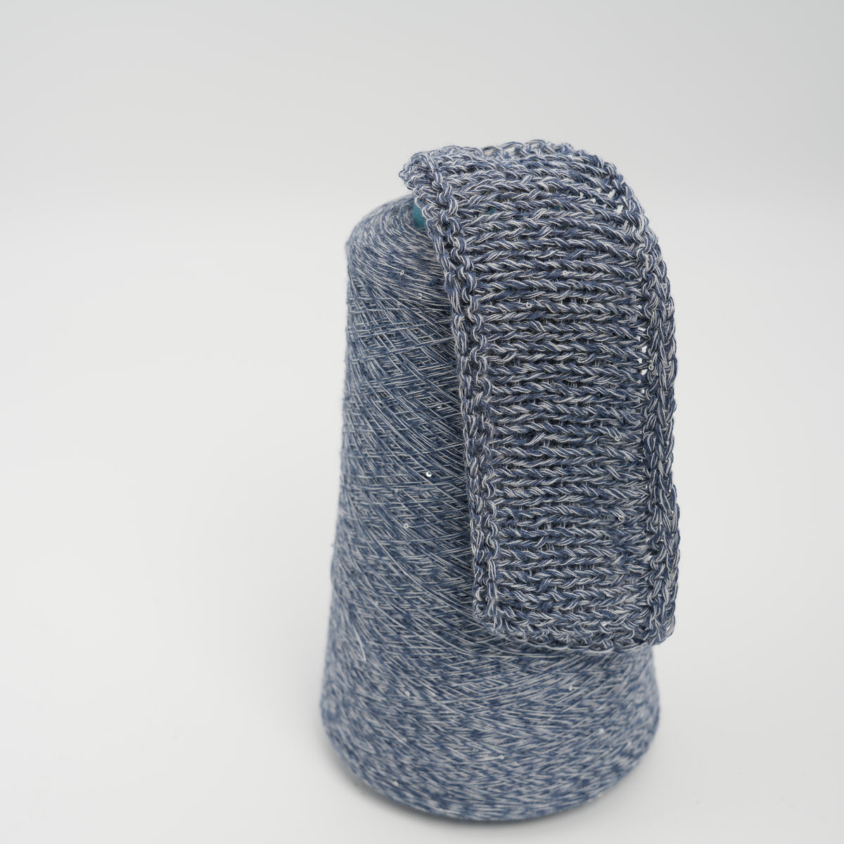 Cone and knitted swatch of Linette cotton and linen blend yarn in Sapphire Melange.