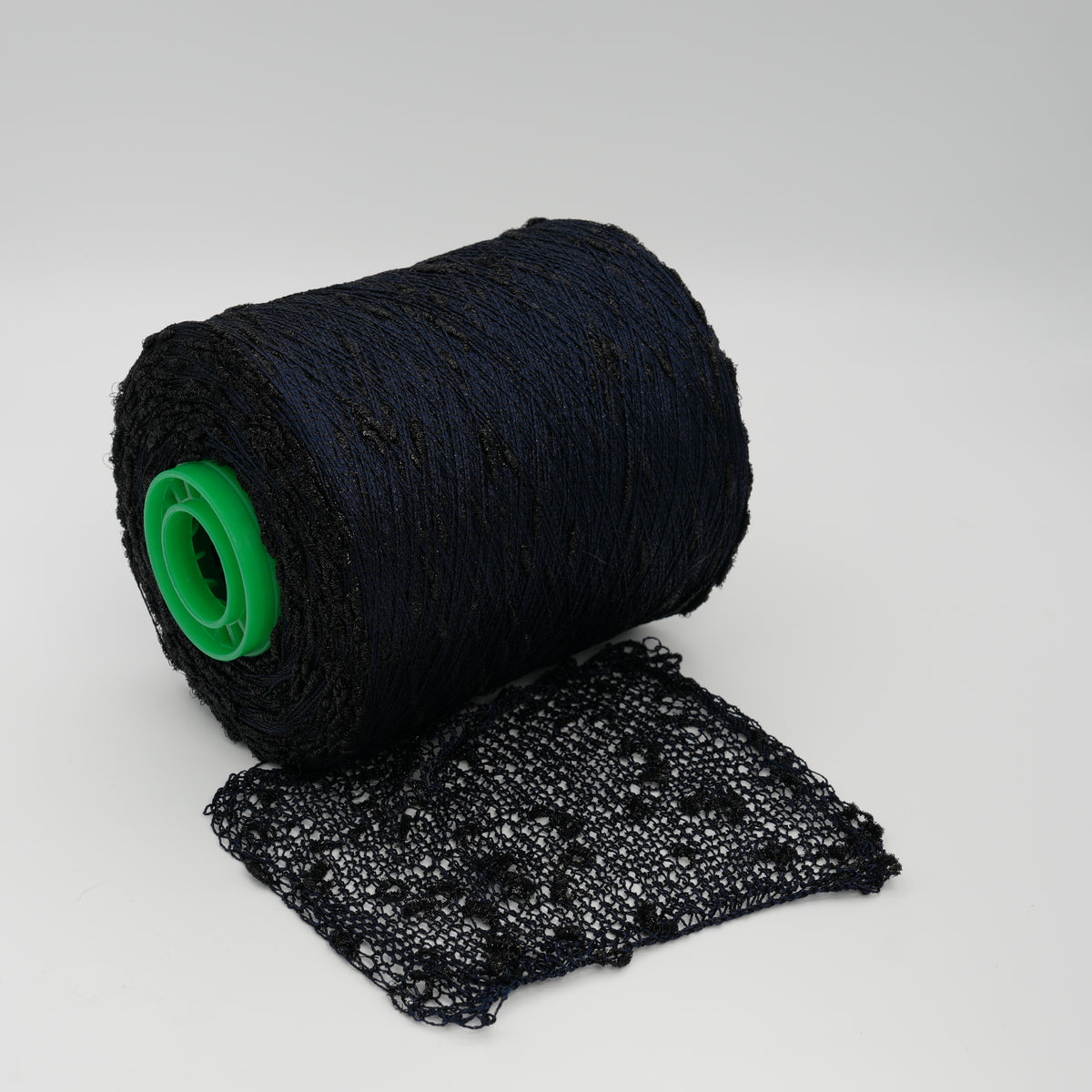 Cone and knitted swatch of Luckystar 6000 viscose and slubbed lurex blend yarn in black.