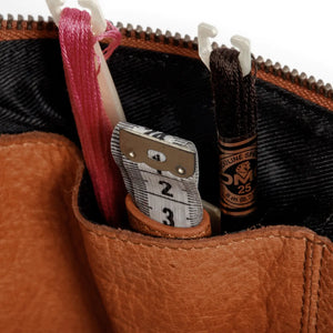 Muud Enturn Leather Project Bag | Black in Whisky. Close-up of exterior pockets holding scissors and a measuring tape.