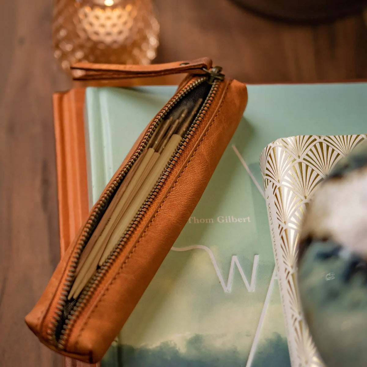 Muud Hee Case | Slim Leather Pouch in Whisky. Slim case opened to show knitting needles beside yarn and a wooden chair.