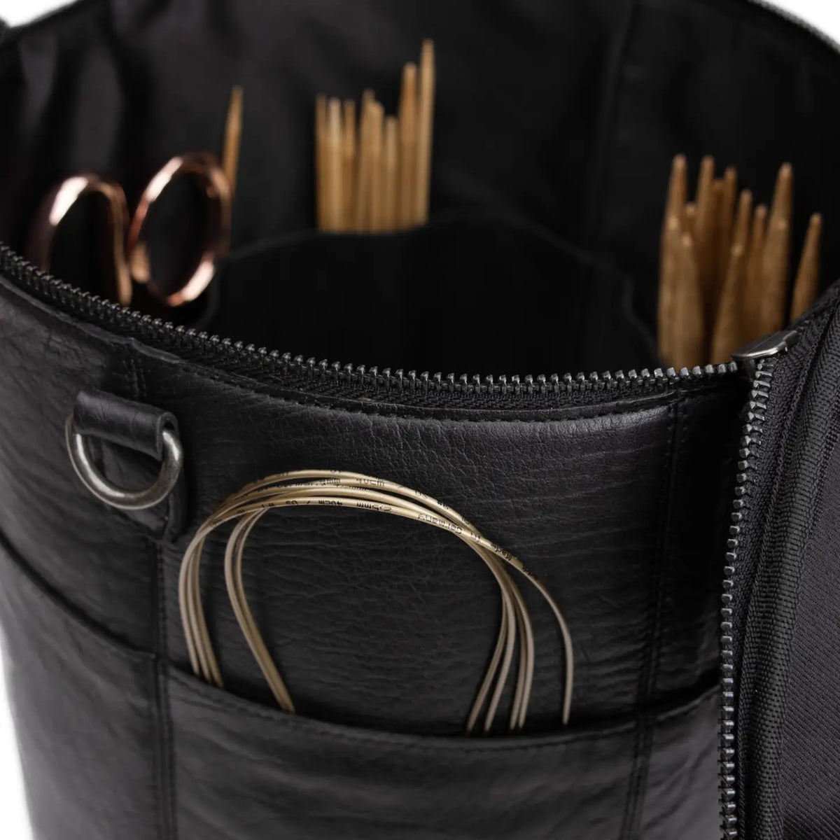 Muud Saturn XL Leather Project Bag in Black. Close-up of exterior pockets holding circular needles and scissors.