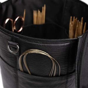 Muud Saturn XL Leather Project Bag in Black. Close-up of exterior pockets holding circular needles and scissors.