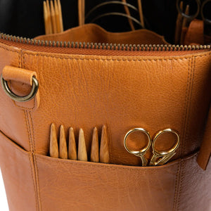Muud Saturn XL Leather Project Bag in Whisky. Close-up of exterior pockets holding needles and scissors.