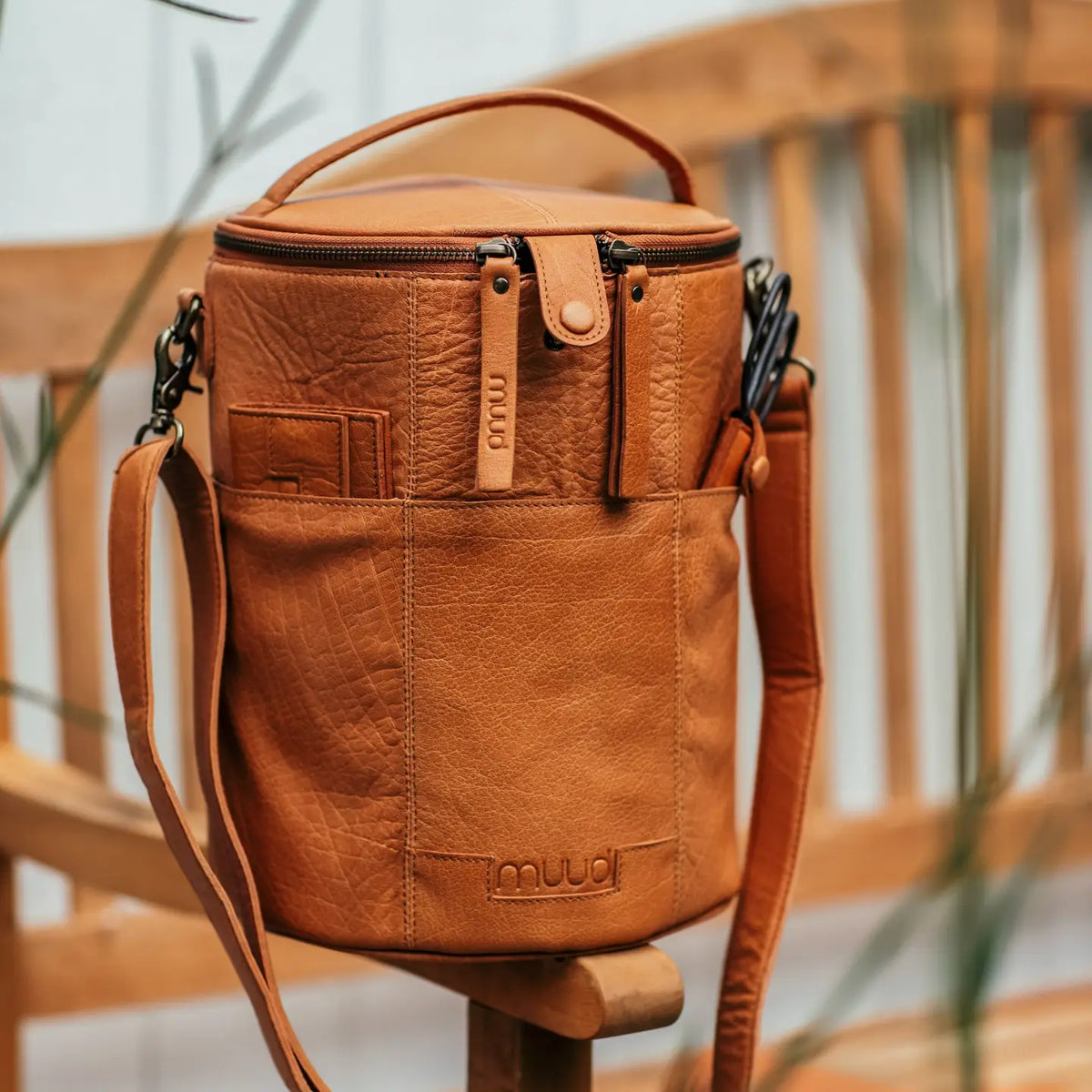 Muud Saturn XL Leather Project Bag in Whisky. Tall leather project bag beside a wooden chair.