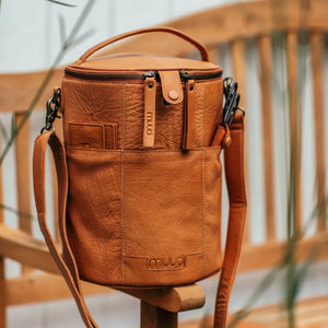 Muud Saturn XL Leather Project Bag in Whisky. Tall leather project bag beside a wooden chair.