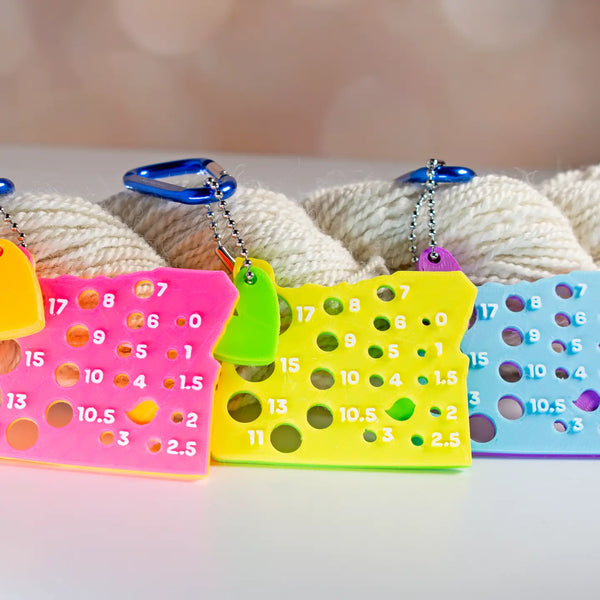 Oregon Needle Gauge | Yellow + Lime. Brightly colored Oregon-shaped needle gauges beside yarn.