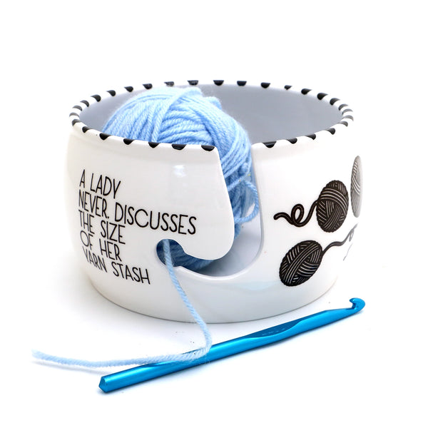 Yarn Bowl. White yarn bowl holding blue yarn beside a crochet hook.